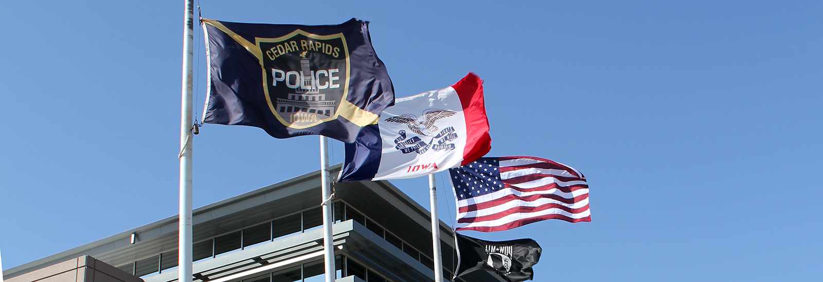 Cedar Rapids Police, State of Iowa, United States, and POW flags waving outside of Police Station