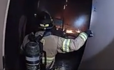 A firefighter is seen responding to a fire in body mounted camera footage from a police officer camera.